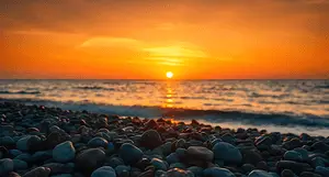 A tranquil beach scene at sunset, featuring colorful skies, gentle waves, and smooth pebbles along t